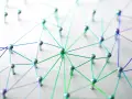 Netzwerk aus silbernen Pins und bunten Fäden auf weißem Untergrund.