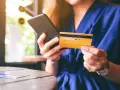 Frau hält Smartphone und goldene Kreditkarte für Online-Shopping.