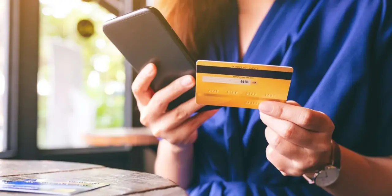 Frau hält Smartphone und goldene Kreditkarte für Online-Shopping.